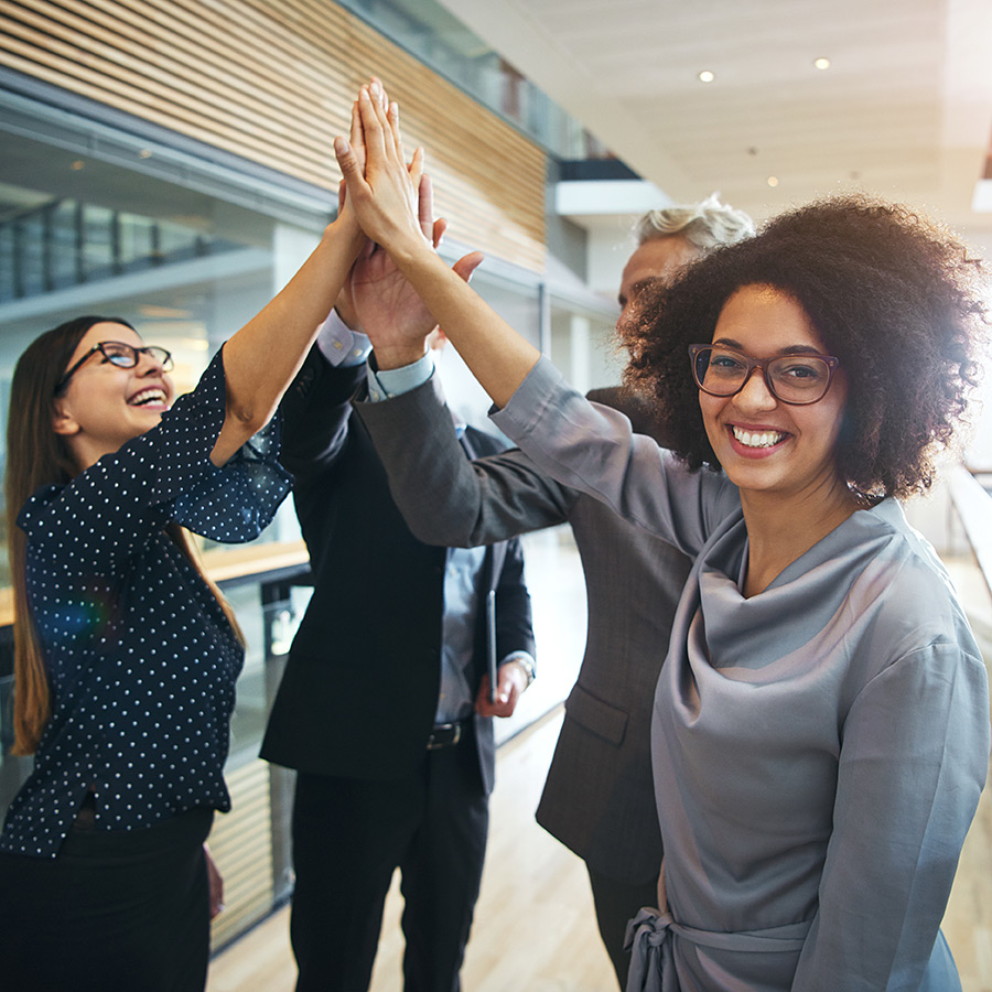 Businesspeople doing highfives in an office environment Businesspeople doing highfives in an office environment